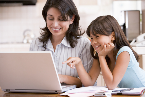 Mom and daughter happily review family cruise option on computer