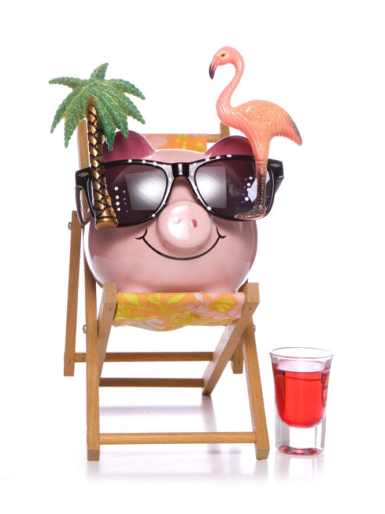 Saving money on family cruises - happy piggy bank sitting on beach chair with vacation items