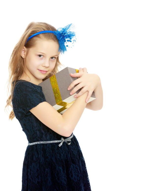 Travel Gift Ideas For Kids | Photo of girl in dress hugging present