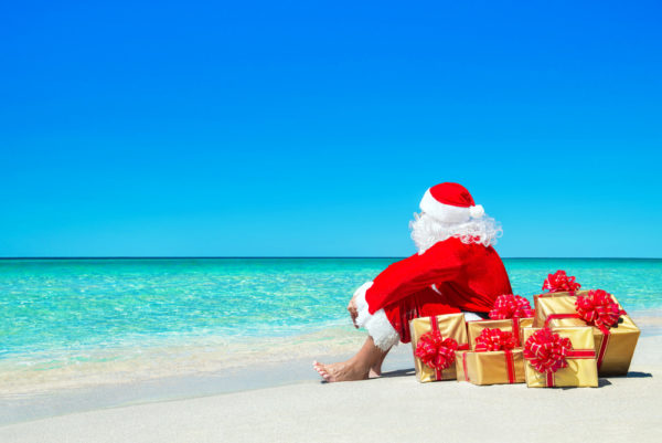 Christmas Cruises - Photo of Santa waiting on beach with pile of gifts