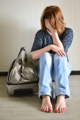 Forgotten Family Passports - photo of sad woman with bag sitting by wall with head in hands