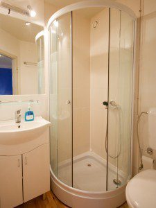 Cruise Ship Rooms - Photo of small bathroom featuring closely clustered sink, shower and toilet.