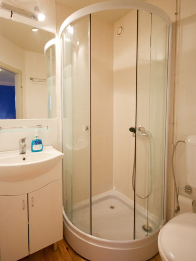 Cruise Hacks for Cruise Ship Rooms - Photo of small bathroom featuring closely clustered sink, shower and toilet.