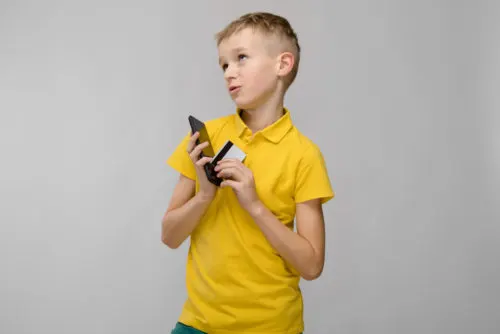 Embarkation Tips | photo of child with holding cell phone and credit card with naughty expression