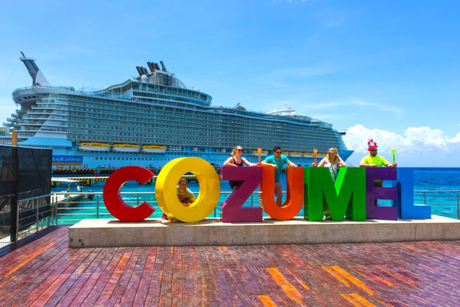 Cozumel Port Day | photo of travelers on city sign with background cruise ship