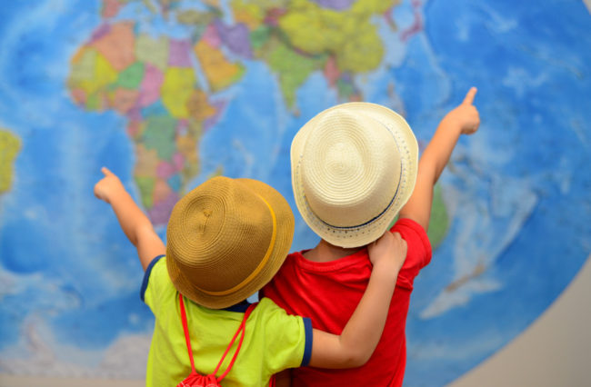 Plan a cruise | Two boys looking at world map and choosing destinations.