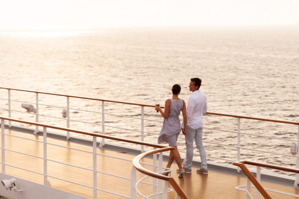 NCL Drink Package | Photo of couple walking on cruise ship deck at sunset with drinks