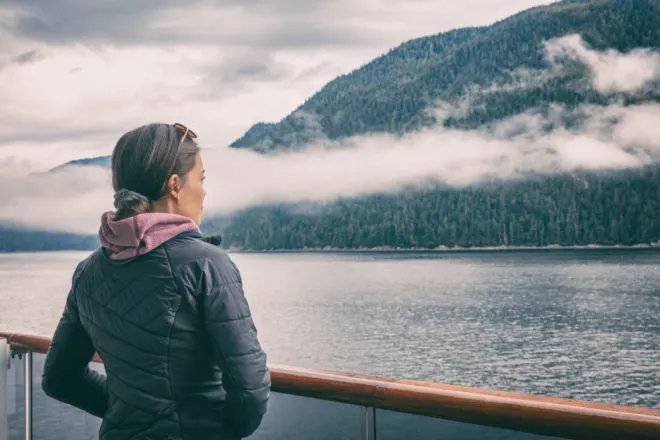 What To Pack For An Alaska Cruise | photo of woman in cozy jacket looking out over ship railing