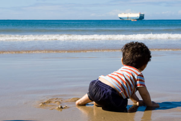 cruising with a baby | photo of baby on beach looking at distant ship