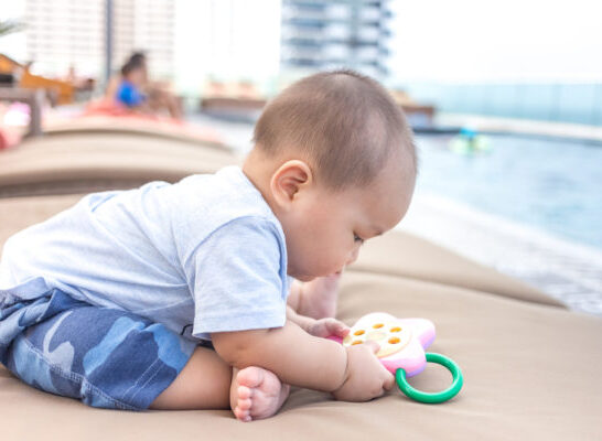 Packing Tips For Cruising With A Baby | Photo of infant playing on poolside lounger