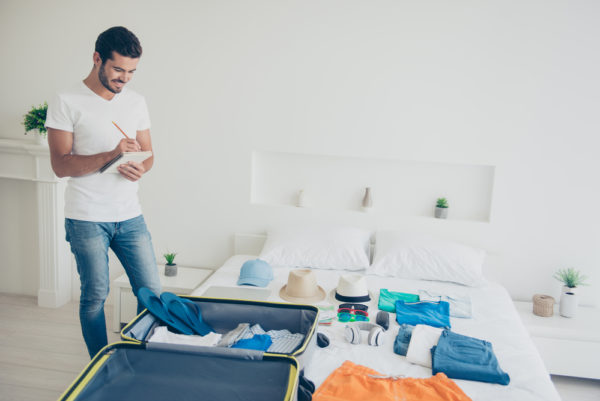 Things To Bring On A Cruise | photo of man packing as he checks list
