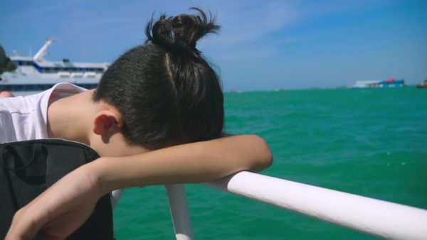 Seasickness on a Cruise | photo of queasy boy with head down on railing