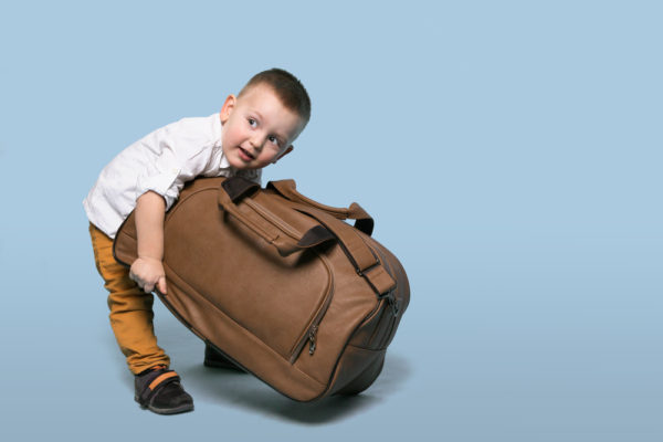 Cruise Carry On Essentials | photo of small toddler trying to lift large carry on bag