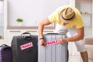 Travel Hacks |photo man placing fragile stickers on suitcases