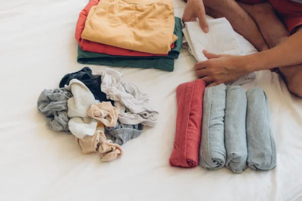 Travel Packing Tips | photo of man folding clothes on bed before trip