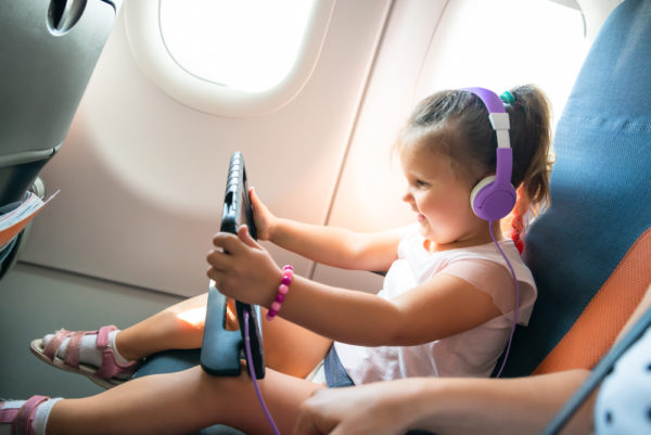 photo of happy small child with tablet and headphones on plane