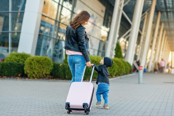 photo of mom and toddler heading into airport with luggage