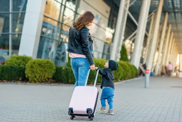 photo of mom and toddler heading into airport with luggage