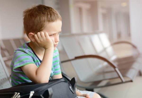 Photo of bored and angry boy sitting at gate waiting for plane.