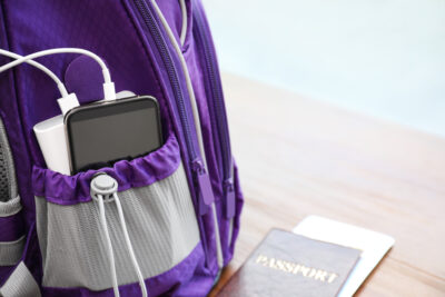 Best Portable Travel Chargers | photo of portable power bank charging cell phone in pocket of backpack next to passport