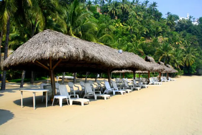 Cozumel Beaches Near Cruise Port | photo of Row of beach cabanas with chairs next to palm trees