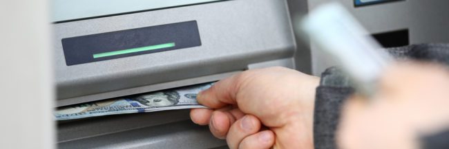 How much cash should I take on a cruise? |Male hands holding bunch of hundred dollars banknotes at ATM machine 