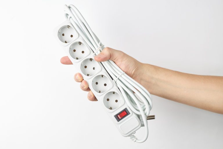 Why No Surge Protector On Cruise Ship | person holds empty white power cord strip. outer space. isolated on white background