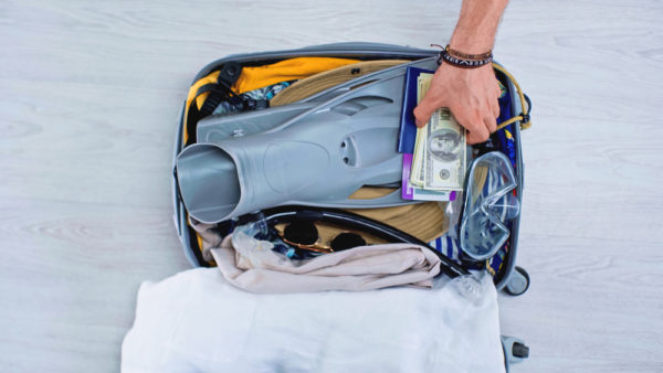 How much money should I take on a cruise ship | photo of man packing suitcase including passport and cash