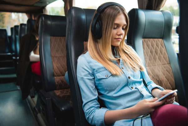Photo of young woman with wireless over-ear headphones riding bus