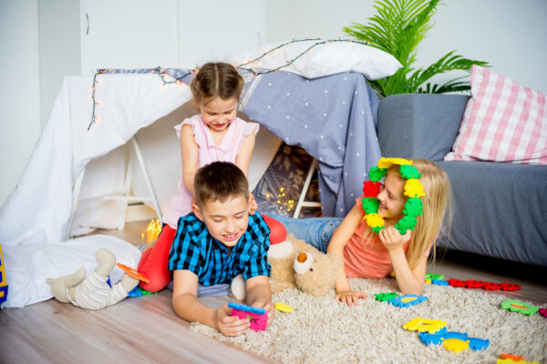 Pop up play tent and other portable play spaces | photo of 3 kids in living area with makeshift tent and toys