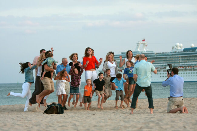 photo of family taking photographs on the beach with their cruise ship in the background.