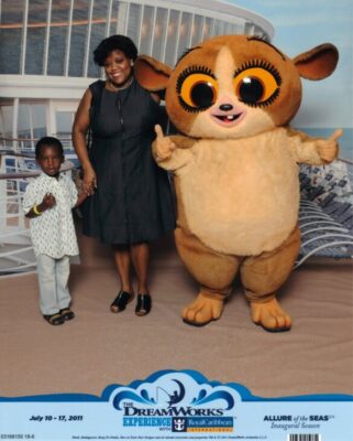 Vintage photo of mother, young child, and Dreamworks character Mort on Royal Caribbean ship.