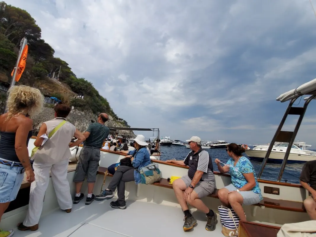Many tour boats hover outside the Blue Grotto, and passengers wait to transfer to rowboats.