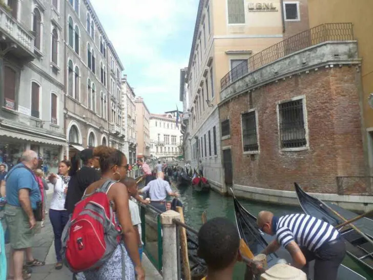 Best Time for a Mediterranean Cruise | Photo of tourists standing along a canal in Venice, Italy, watching gondoliers prepare their boats for rides.