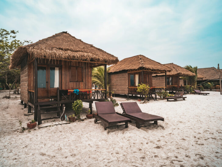 Rustic beachfront huts with thatched roofs on a white sand beach in Asia, offering a peaceful and natural retreat by the sea.