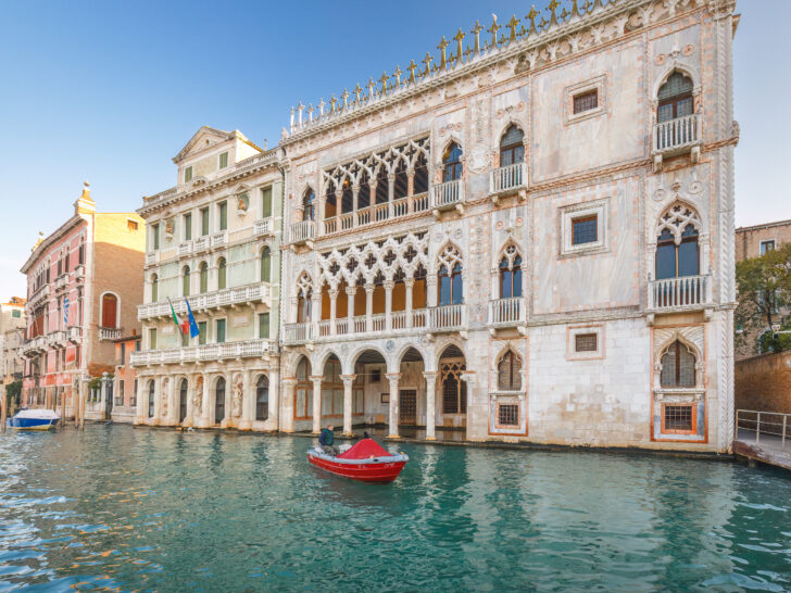 Venetian Gothic architecture along Venice’s Grand Canal, with a small red boat floating in the foreground.