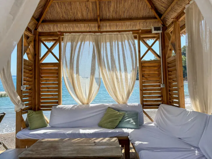 Private beach cabana with flowing curtains and soft seating, offering a peaceful spot by the water’s edge at an upscale resort.