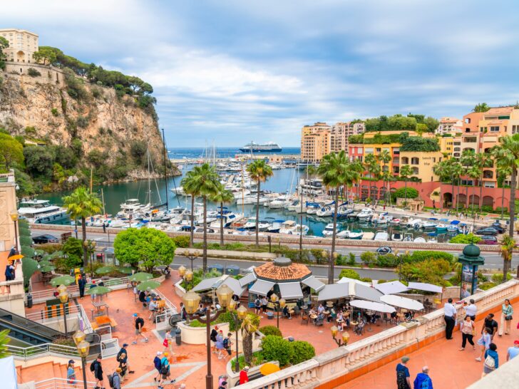 View of Monaco’s Port of Fontvieille with yachts docked in the marina and a cruise ship visible in the far distance.