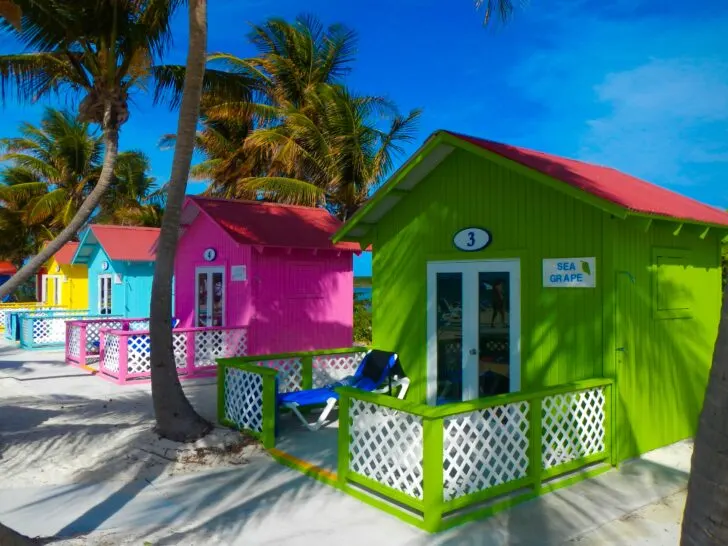 Brightly painted beachfront cabanas at Princess Cays, surrounded by palm trees and pristine white sand, providing an ideal spot for relaxation on this exclusive Princess Cruises island.