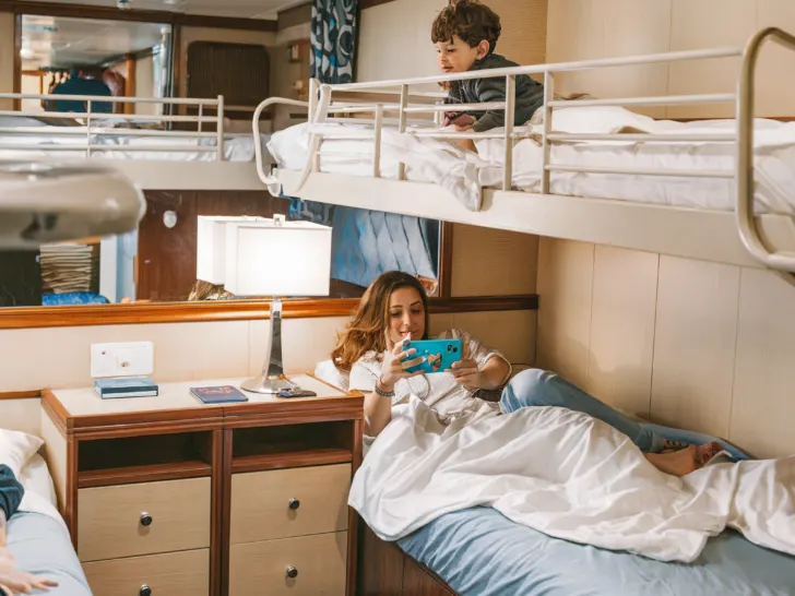 Family inside cruise cabin with a comfortable bunk bed setup, ideal for accommodating children and parents in a compact space.