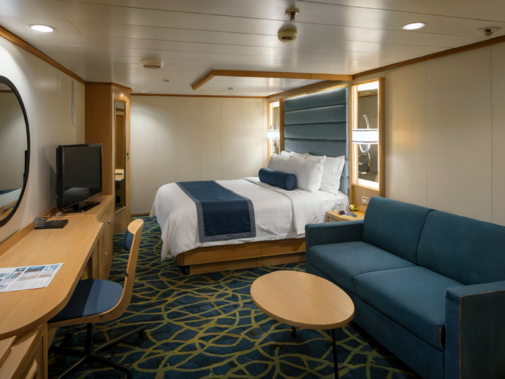 Interior view of an inside cruise cabin with a comfortable bed, small desk area, and seating, ideal for budget-conscious travelers.