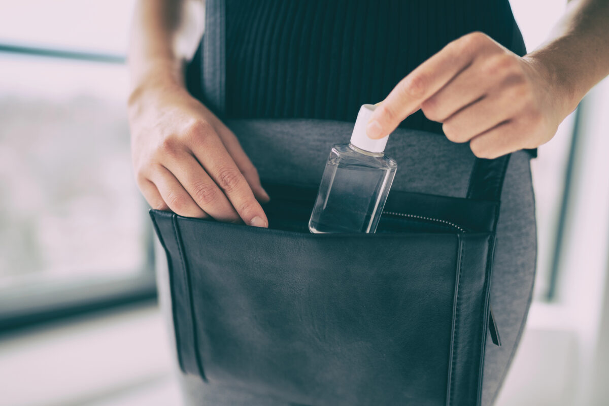 Traveler storing hand sanitizer in a bag, highlighting the importance of carrying personal disinfectant while on a cruise vacation.