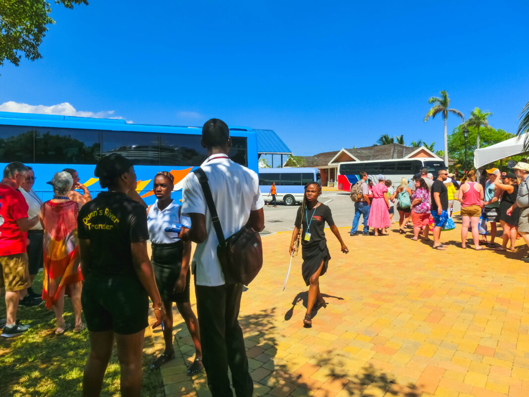 A busy excursion meeting point in Jamaica, where guides coordinate tour groups and passengers line up for their buses.