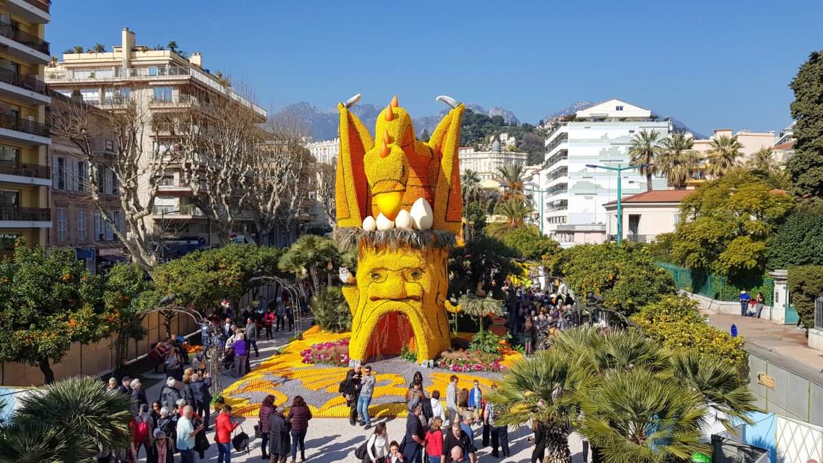 A large citrus sculpture featuring a dragon and a mythical face stands tall at the Menton Lemon Festival, a vibrant Mediterranean festival celebrating the region’s citrus heritage.