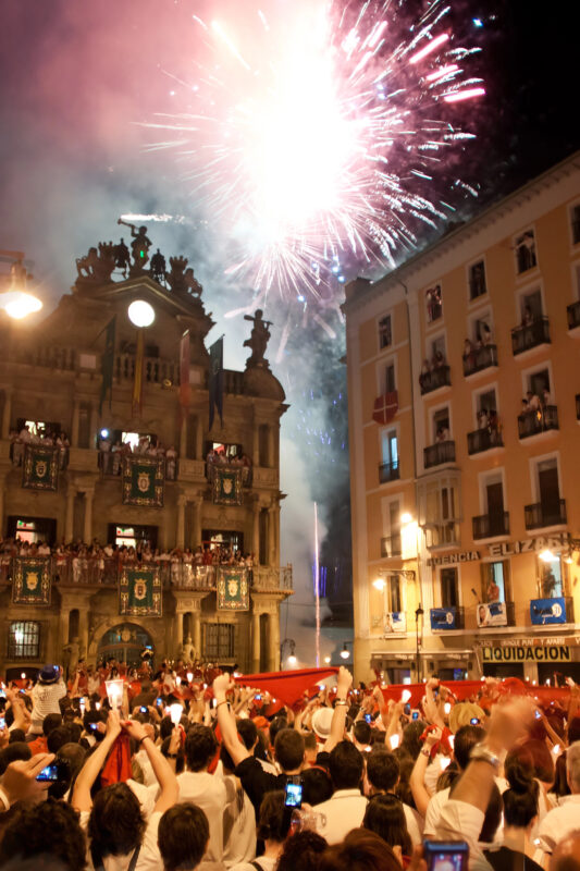 A massive crowd in Pamplona gathers in front of the historic town hall to watch fireworks marking the end of the San Fermín Festival, a famous Mediterranean festival.