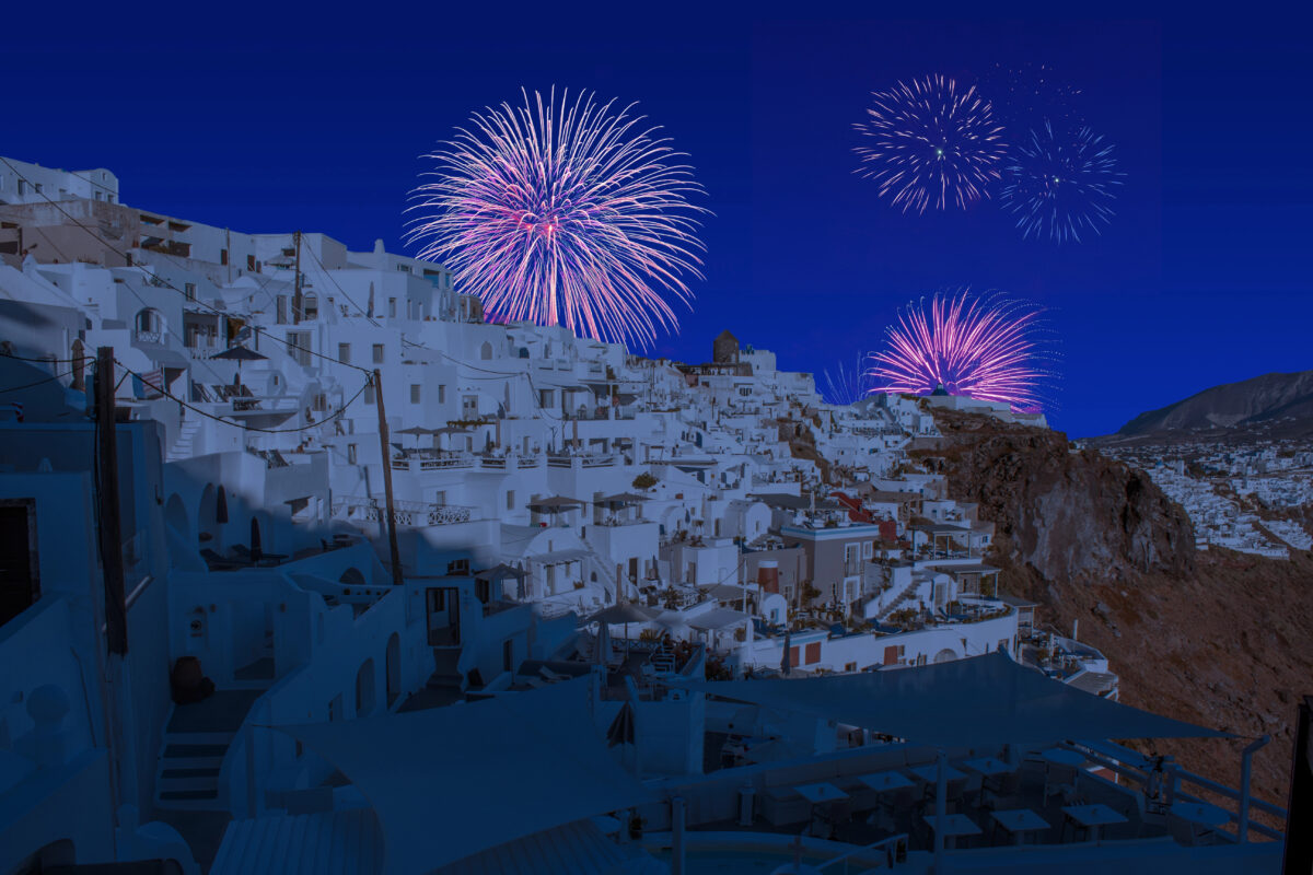 Bright pink and purple fireworks explode over Santorini’s whitewashed buildings, celebrating one of the island’s vibrant Mediterranean festivals.