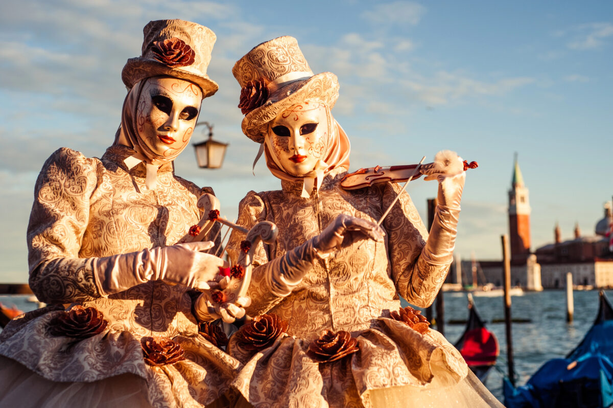 A pair of masked performers dressed in baroque-inspired outfits capture the spirit of Venice Carnival, a highlight of Mediterranean festivals known for its rich history and artistic traditions.