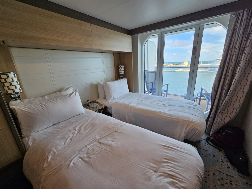Interior of a cruise cabin featuring two beds and a balcony, used to demonstrate real-life examples of cruise cabin organization.