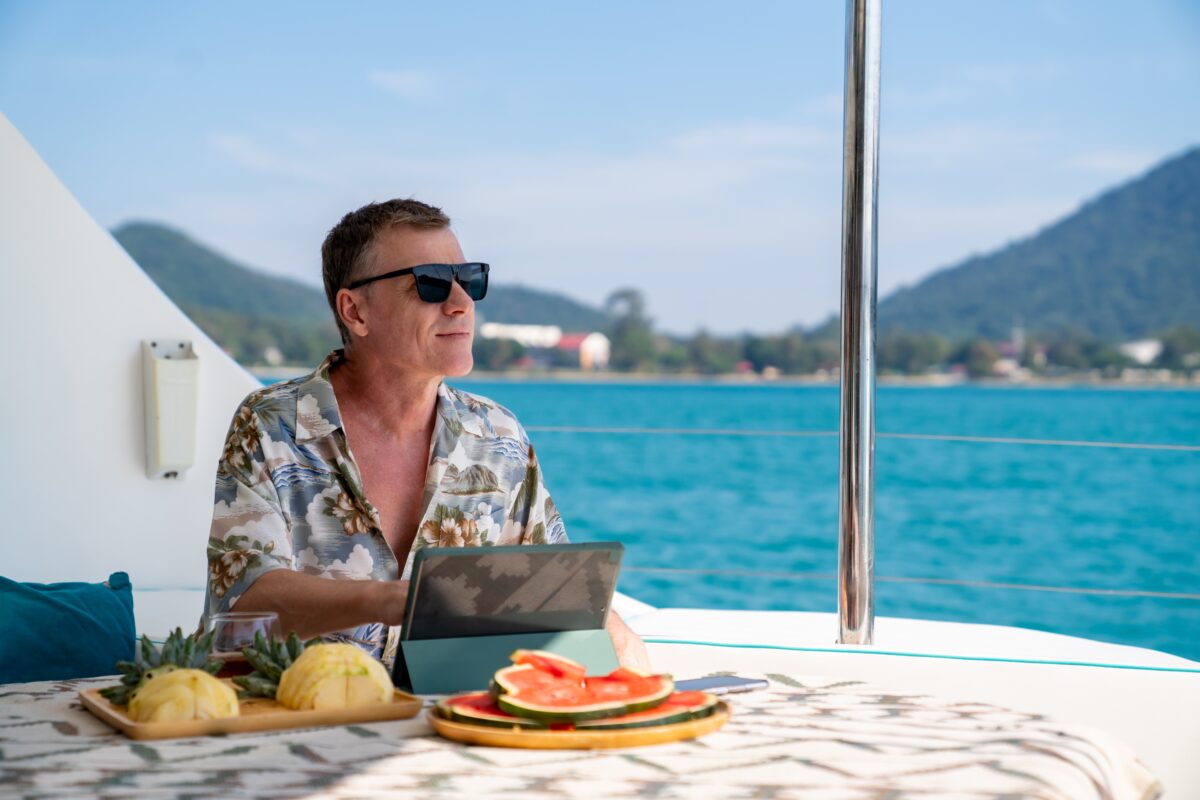 Man using a tablet on a cruise with tropical views and fresh fruit
