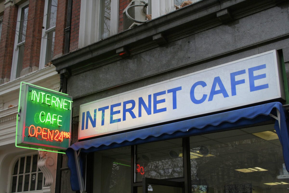 Exterior of a classic internet café with neon sign and 24-hour access